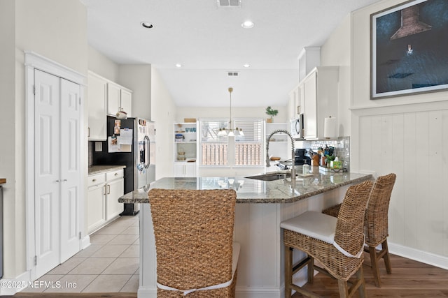 kitchen featuring white cabinetry, sink, dark stone countertops, hanging light fixtures, and stainless steel appliances