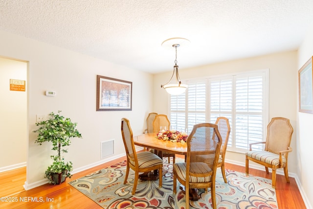 dining space featuring light hardwood / wood-style flooring and a textured ceiling