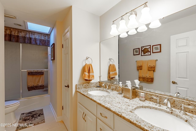 full bathroom with enclosed tub / shower combo, a skylight, vanity, tile patterned floors, and toilet