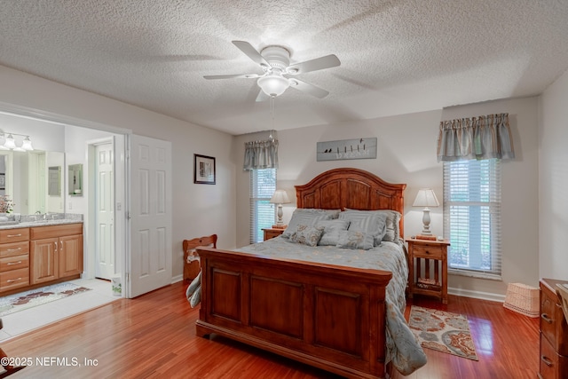 bedroom featuring multiple windows, connected bathroom, and light wood-type flooring