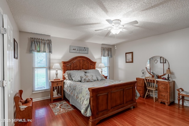 bedroom with ceiling fan, hardwood / wood-style floors, and a textured ceiling