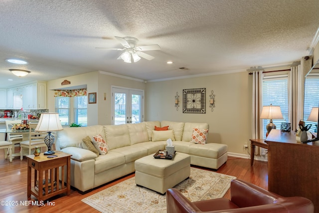 living room with ornamental molding, light hardwood / wood-style floors, french doors, and ceiling fan