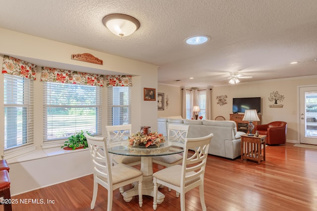 dining space featuring ceiling fan, a healthy amount of sunlight, light hardwood / wood-style floors, and a textured ceiling