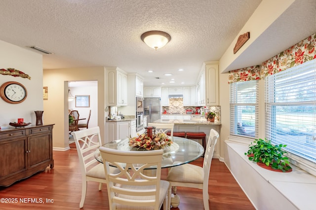 dining space with dark hardwood / wood-style floors and a textured ceiling