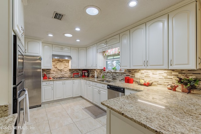 kitchen with stainless steel appliances, white cabinetry, sink, and light stone counters