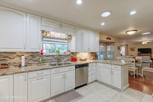 kitchen featuring dishwasher, sink, backsplash, light stone counters, and kitchen peninsula