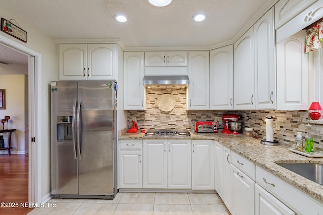 kitchen featuring light stone counters, stainless steel appliances, light tile patterned floors, and white cabinets