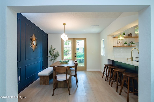 dining area with french doors, sink, and light hardwood / wood-style floors