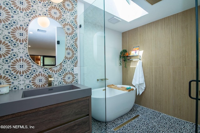 bathroom with a skylight, tile walls, tile patterned flooring, vanity, and a bath