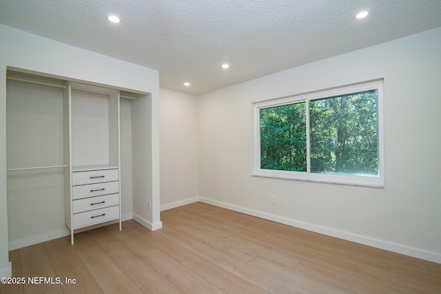 unfurnished bedroom with light hardwood / wood-style flooring, a closet, and a textured ceiling