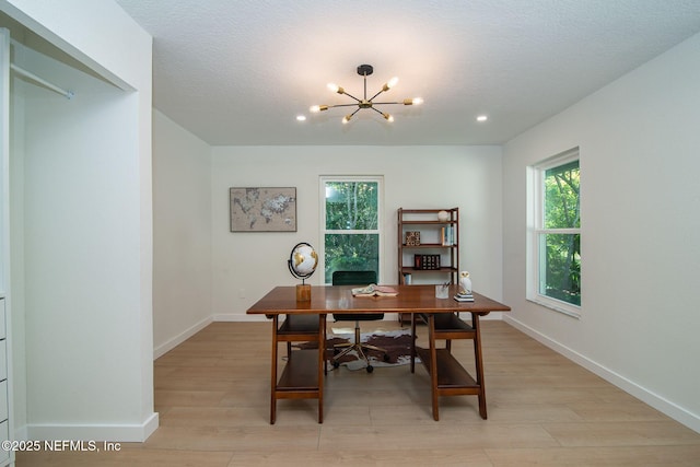 home office featuring plenty of natural light, light hardwood / wood-style floors, and a notable chandelier