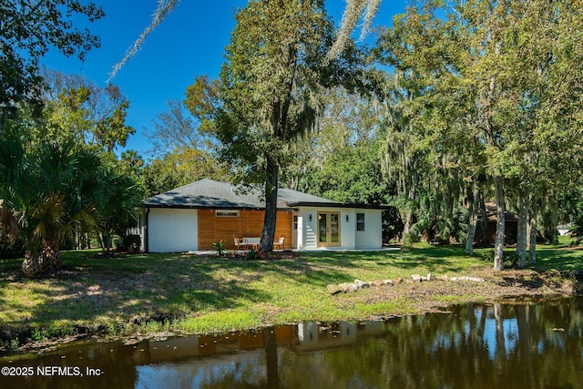 back of house with a water view and a lawn