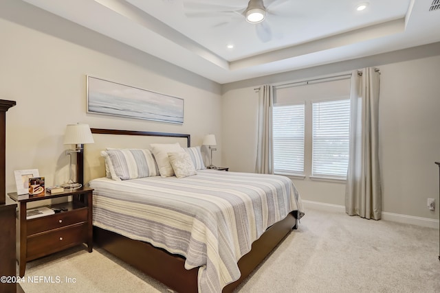 bedroom with light carpet, a tray ceiling, and ceiling fan