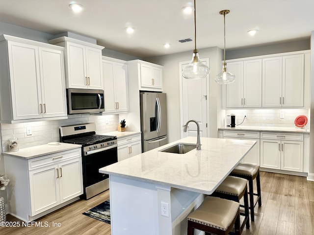 kitchen with white cabinetry, stainless steel appliances, and a kitchen island with sink