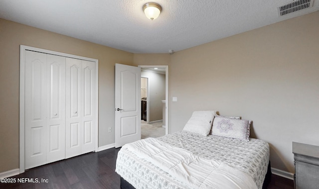 bedroom with a textured ceiling, dark wood-type flooring, visible vents, baseboards, and a closet