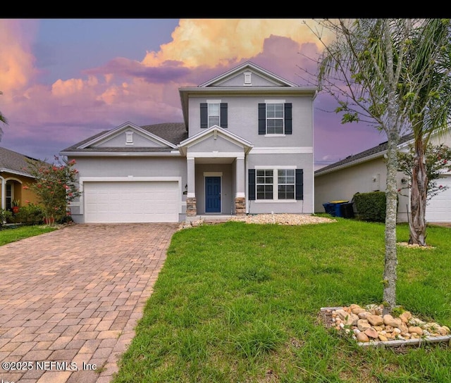 traditional home featuring a garage, a yard, decorative driveway, and stucco siding