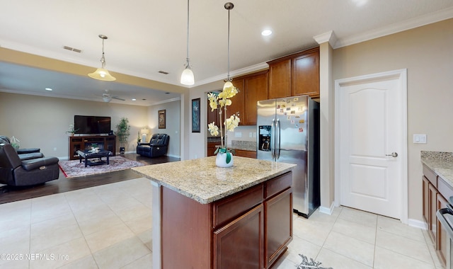 kitchen featuring stainless steel fridge with ice dispenser, a kitchen island, light stone counters, open floor plan, and decorative light fixtures