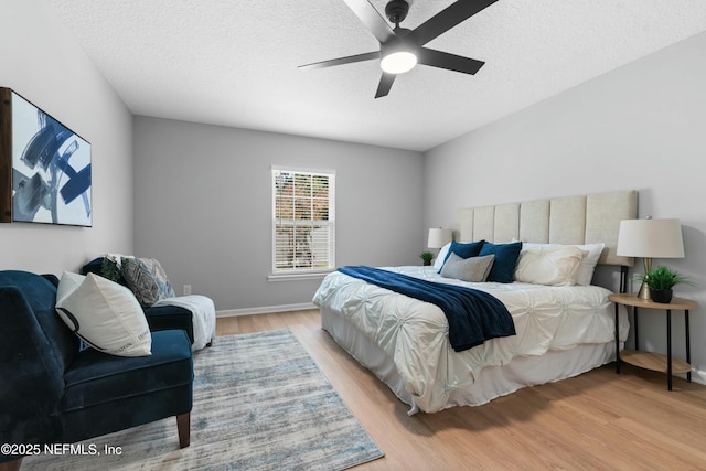 bedroom with ceiling fan, a textured ceiling, and light wood-type flooring