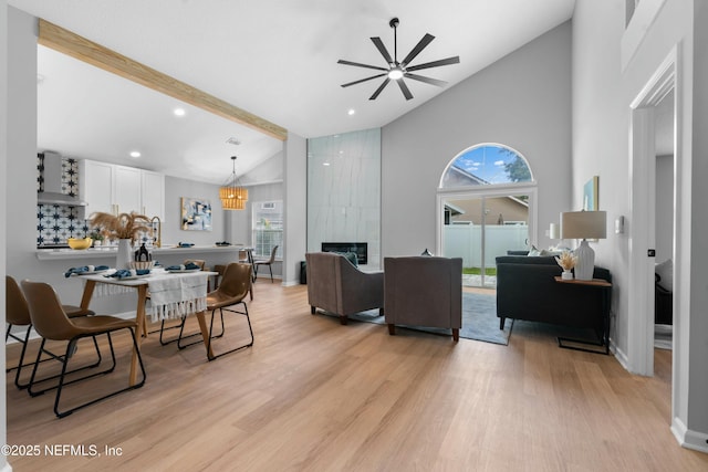 living room with high vaulted ceiling, beam ceiling, a high end fireplace, and light hardwood / wood-style floors