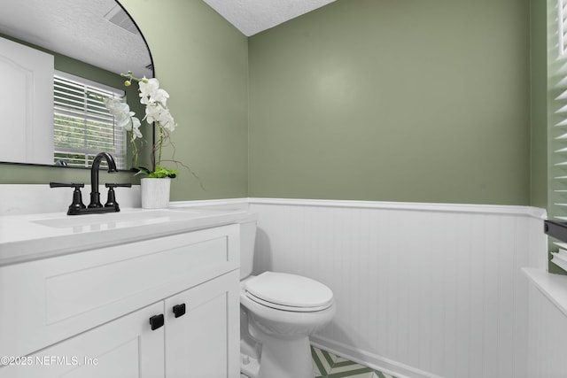 bathroom with vanity, a textured ceiling, and toilet