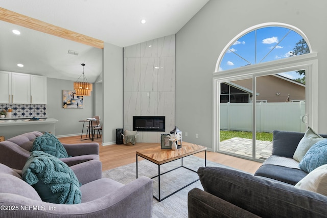 living room with a premium fireplace, high vaulted ceiling, beam ceiling, and light wood-type flooring