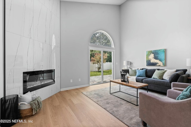 living room featuring a towering ceiling, light hardwood / wood-style floors, and a large fireplace