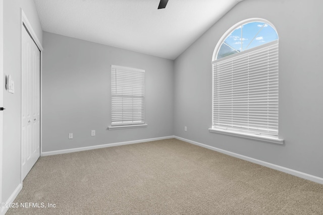 unfurnished bedroom featuring lofted ceiling, a closet, ceiling fan, and carpet flooring