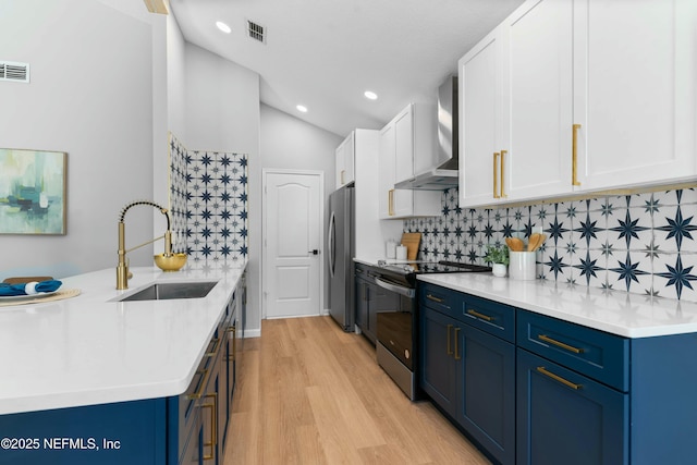 kitchen featuring electric stove, white cabinetry, sink, stainless steel fridge, and wall chimney exhaust hood