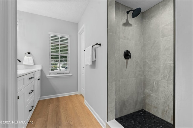 bathroom with vanity, hardwood / wood-style floors, a textured ceiling, and a tile shower