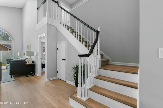 stairway with hardwood / wood-style floors and a towering ceiling