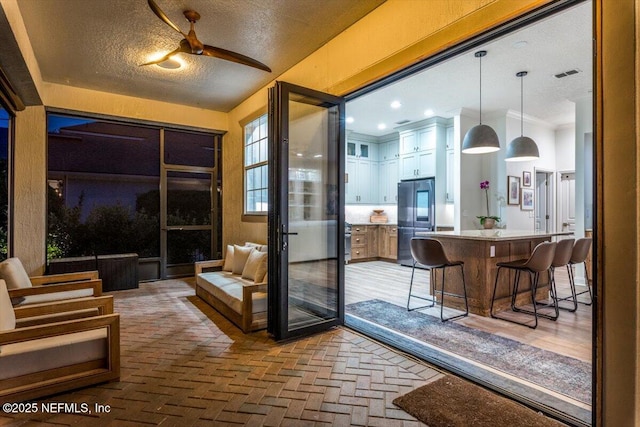 interior space with visible vents, a textured ceiling, brick floor, and ornamental molding