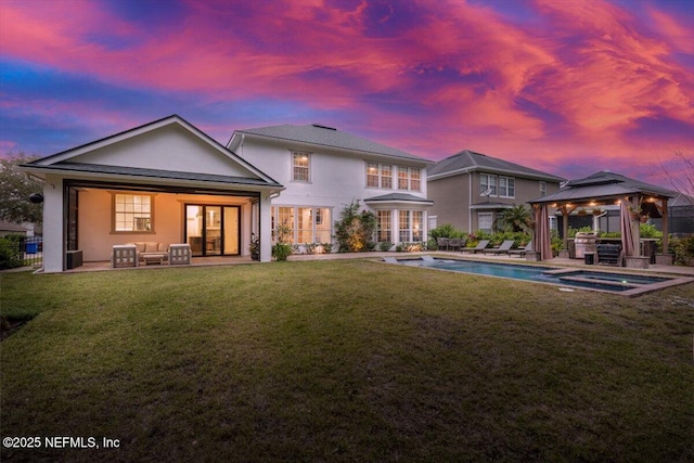 back of property with an outdoor living space, stucco siding, a gazebo, a patio area, and a lawn