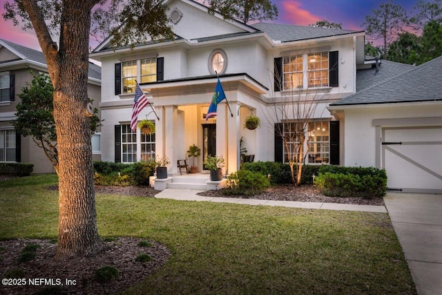 view of front of home with a garage, stucco siding, a shingled roof, and a front lawn