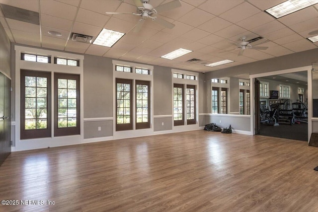 empty room with visible vents, a paneled ceiling, ceiling fan, and wood finished floors