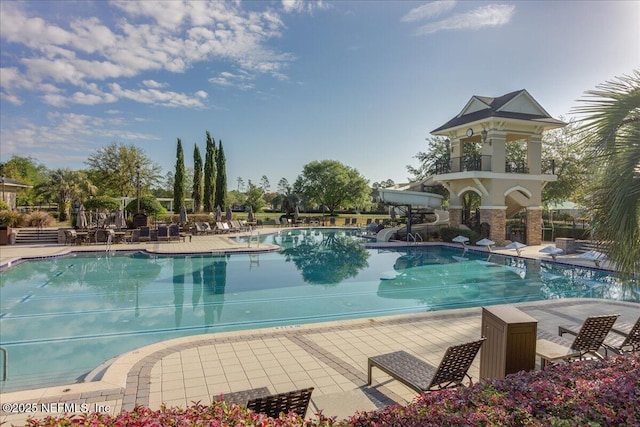 community pool with a water slide and a patio area