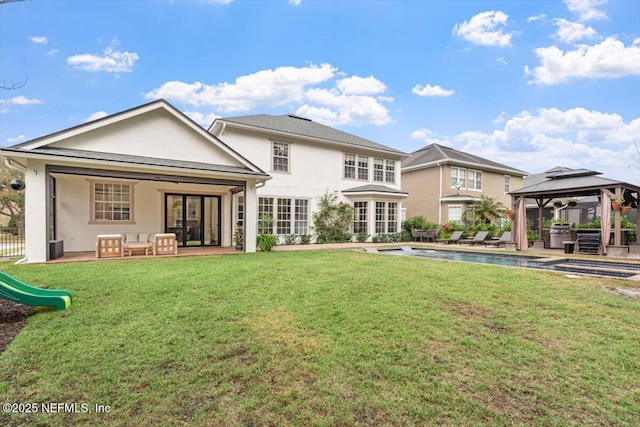 back of property with a gazebo, stucco siding, a patio, and a yard