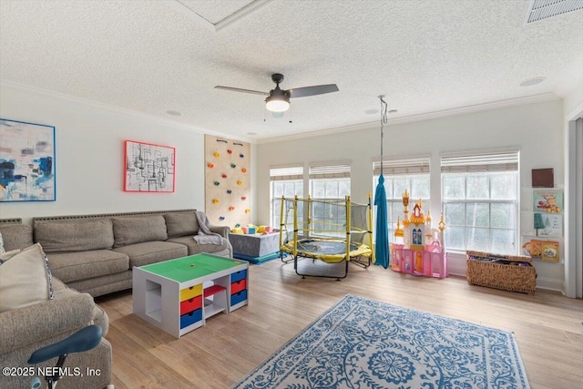 living room featuring visible vents, ornamental molding, a ceiling fan, and wood finished floors