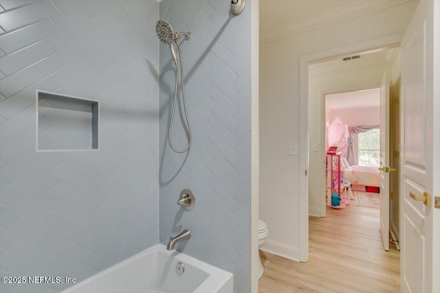 full bath featuring toilet, ornamental molding, wood finished floors, baseboards, and shower / bathtub combination