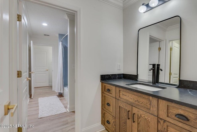 bathroom featuring wood finished floors, shower / bath combo with shower curtain, ornamental molding, and vanity