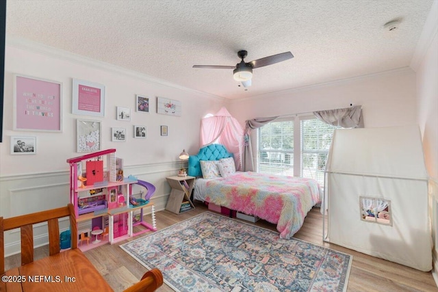 bedroom with a wainscoted wall, wood finished floors, and crown molding