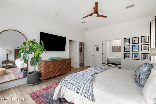 bedroom with visible vents, connected bathroom, ceiling fan, and wood finished floors