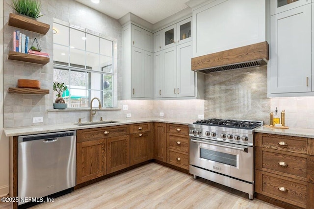 kitchen featuring open shelves, a sink, extractor fan, appliances with stainless steel finishes, and brown cabinets
