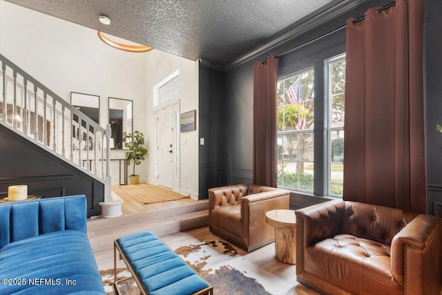 living room with stairway, a textured ceiling, a healthy amount of sunlight, and wood finished floors