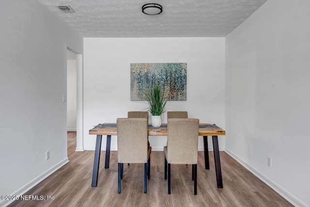 dining area featuring wood-type flooring and a textured ceiling