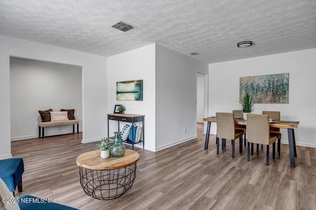 dining area with hardwood / wood-style flooring and a textured ceiling