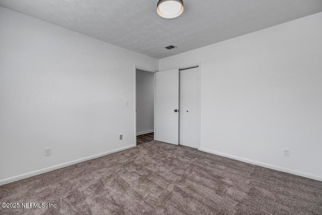 unfurnished bedroom with carpet, a textured ceiling, and a closet