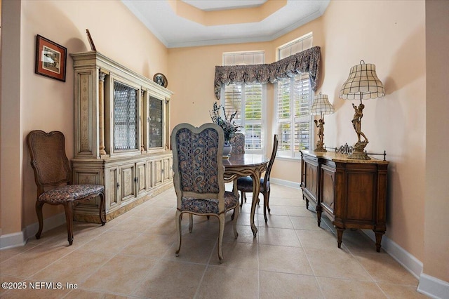 tiled dining room with crown molding and a raised ceiling