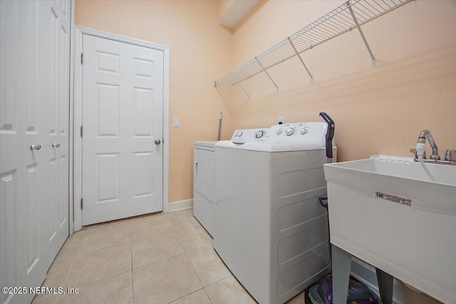 laundry room featuring washer and dryer, sink, and light tile patterned floors