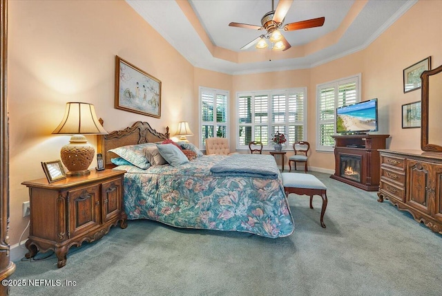 carpeted bedroom with a raised ceiling, ornamental molding, and ceiling fan