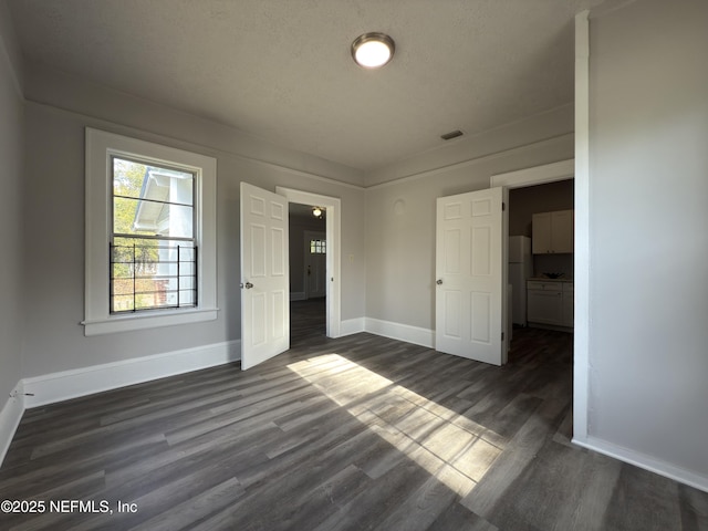 6624 Avalon St, Jacksonville, FL 32208 - unfurnished bedroom featuring freestanding refrigerator, dark wood-type flooring, baseboards, and visible vents